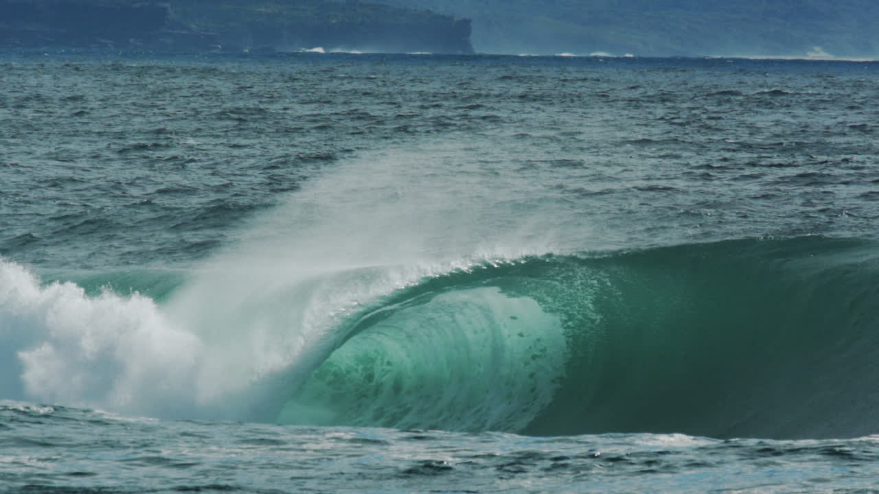 Clear green wave erupts into air as mist and foam scatter, telephoto slow motion shot