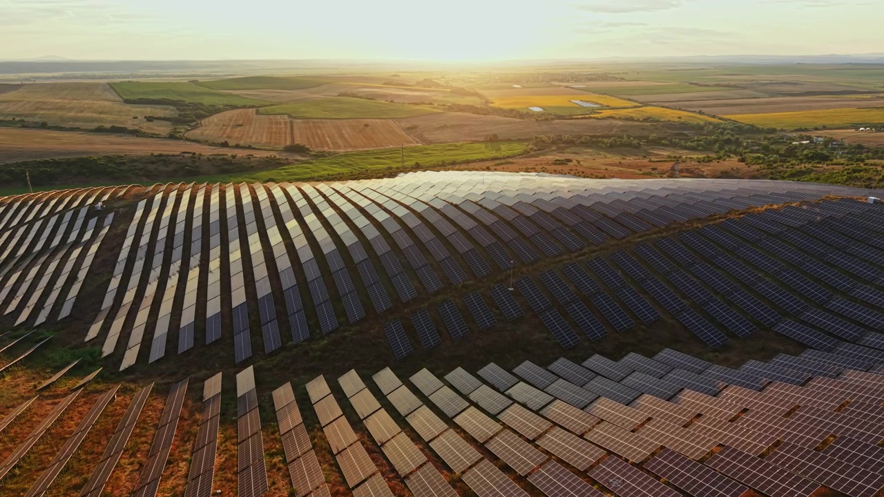 Solpaneler dækker et stort åbent område ved solnedgang, hvor de fanger sollys for at generere energi til nærliggende samfund og reducere afhængigheden af fossile brændstoffer