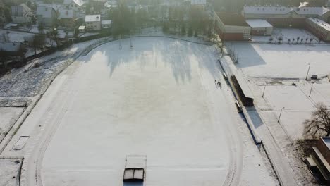 group-of-runners-exercising-on-snowy-running-track,-winter-morning-exercising-aerial-shot