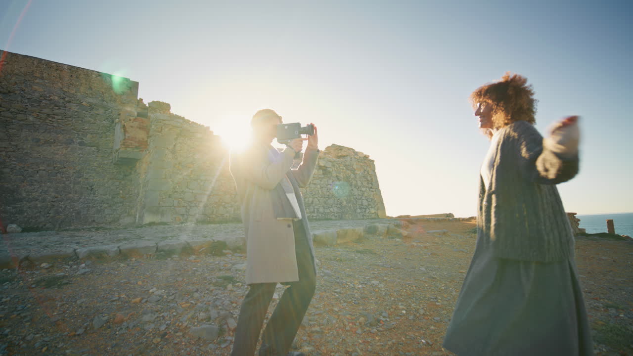 Photographer filming model evening beach. Joyful couple taking video at shore