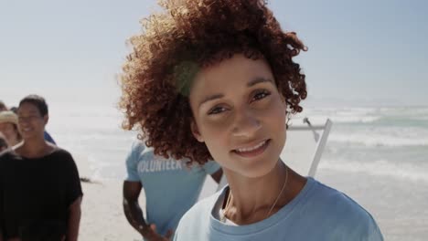 Front-view-of-African-american-female-volunteer-looking-at-camera-on-the-beach-4k
