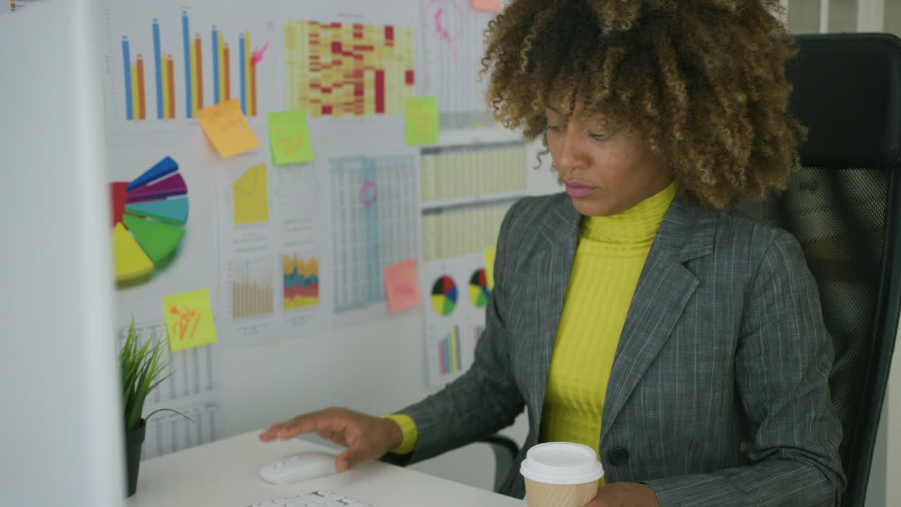 Young worker having coffee while using computer