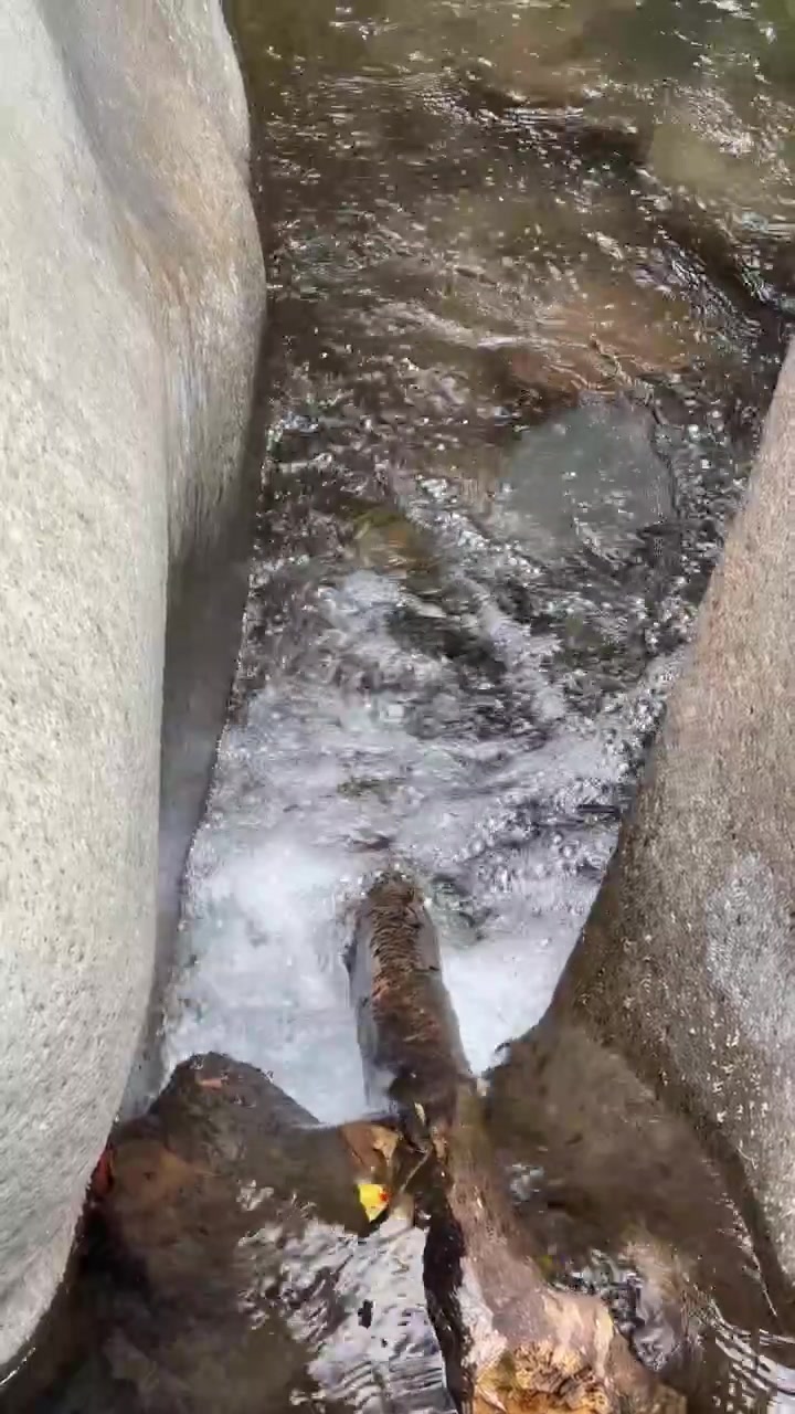 Água cristalina fluindo entre grandes rochas lisas de rio