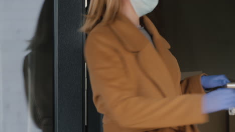 a woman wears a protective mask at the exit of the house