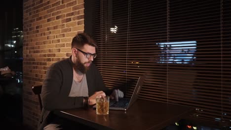 man working on laptop in a bar at night