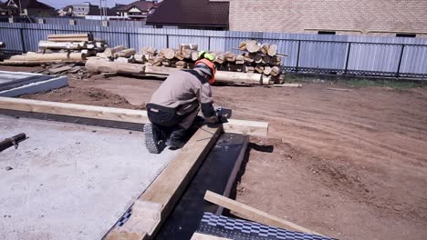 construction worker laying wooden beams on foundation