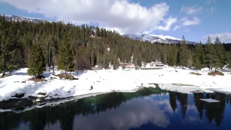 Luftaufnahme-über-Einem-See-Im-Caumasee-In-Der-Schweiz,-Gefrorene-Landschaft-Mit-Bäumen-Und-Die-Spiegelung-Des-Himmels-Im-Seewasser