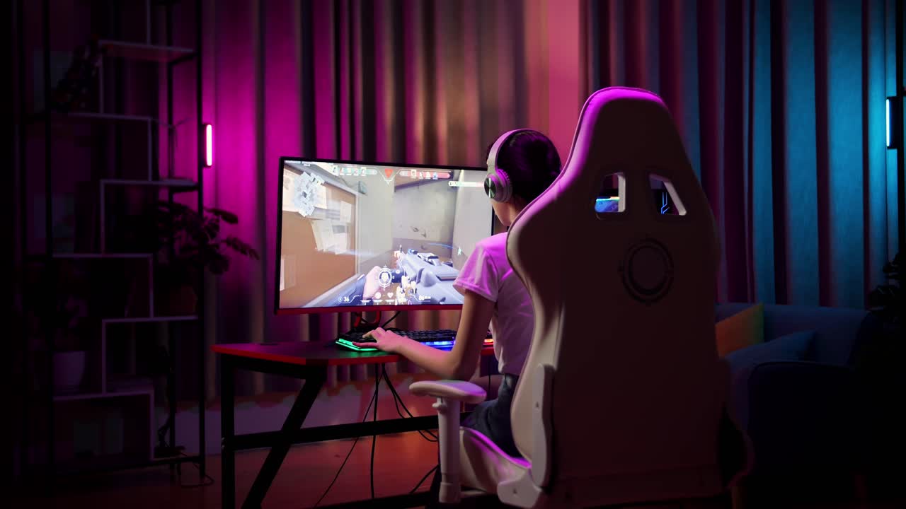 Adolescente asiatica gamer entusiasta festeggia la vittoria mentre gioca a un videogioco sparatutto online al computer.