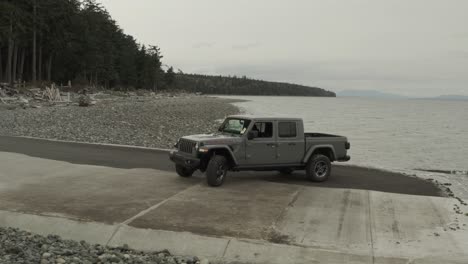 drone shoot of a grey jeep gladiator on the beach, in 4k