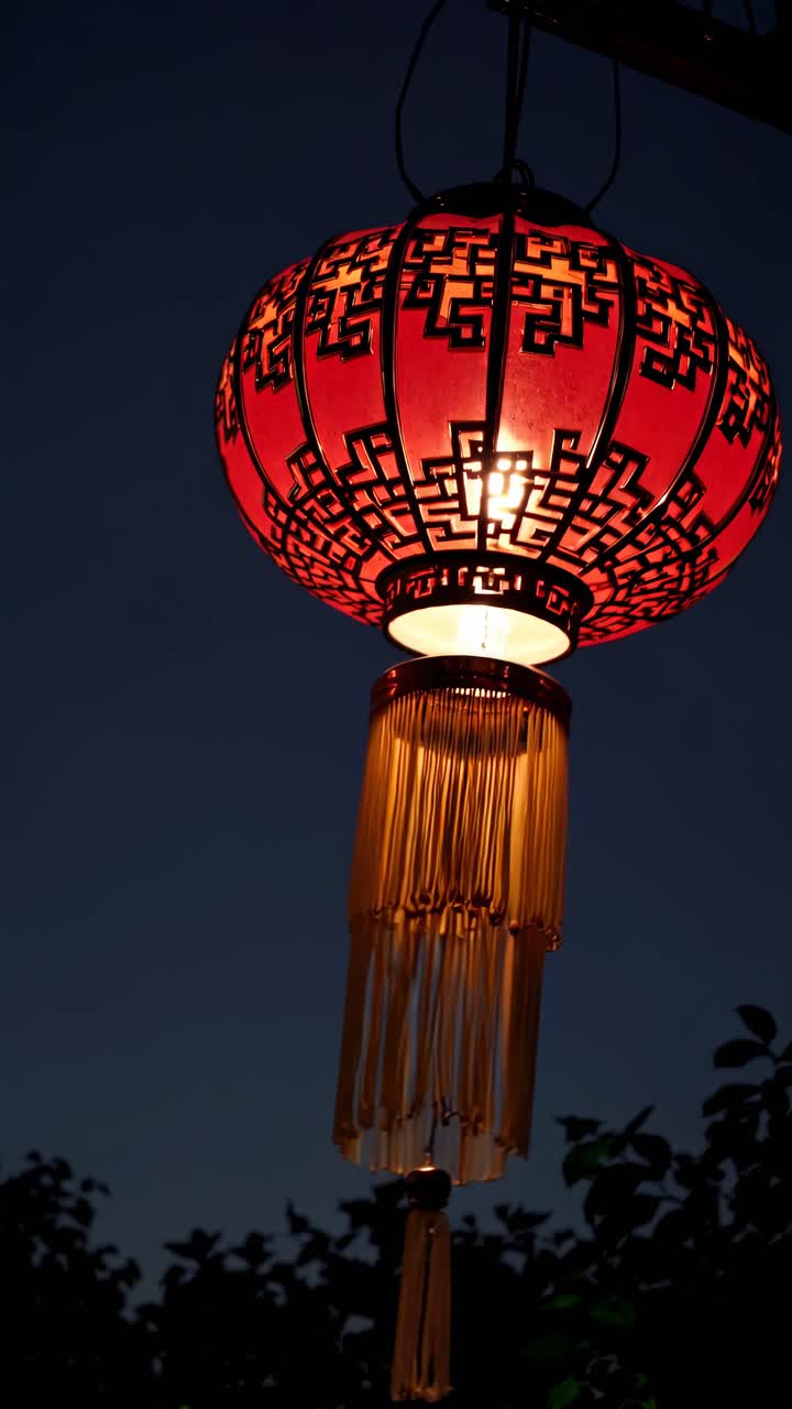 Low-angle video shot of a traditional red lantern with intricate patterns, glowing warmly