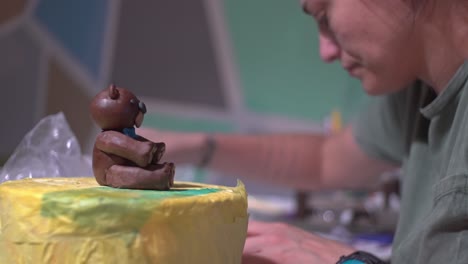 side view of caucasian woman decorating a cake with sugar paste fondant bear at home