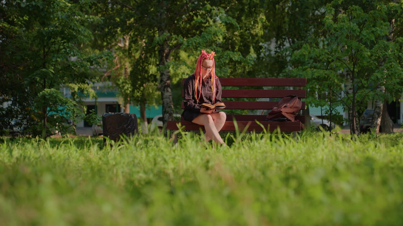 quiet urban afternoon, serene park setting with thoughtful woman, lone female sitting on park bench in afternoon sunlight, solitary woman with pink hair ponders in tranquil city park environment