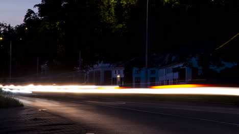 time lapse of headlights from fast driving cars flashing past camera - zoom out