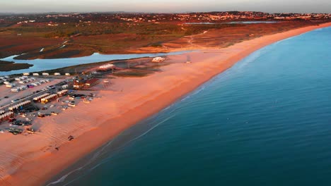 gran toma aérea desde la playa de arena hasta el horizonte de la ciudad de armação de pêra al atardecer