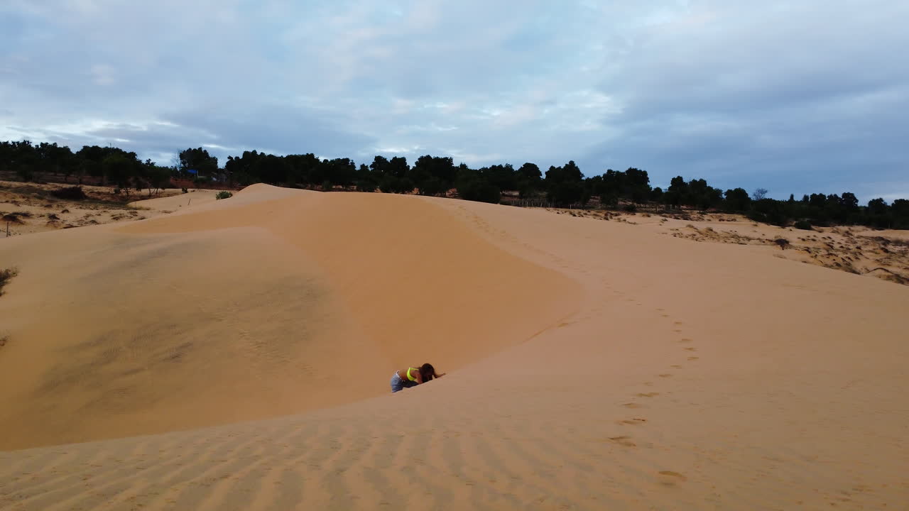 mujer caminando por las dunas de arena roja en vietnam
