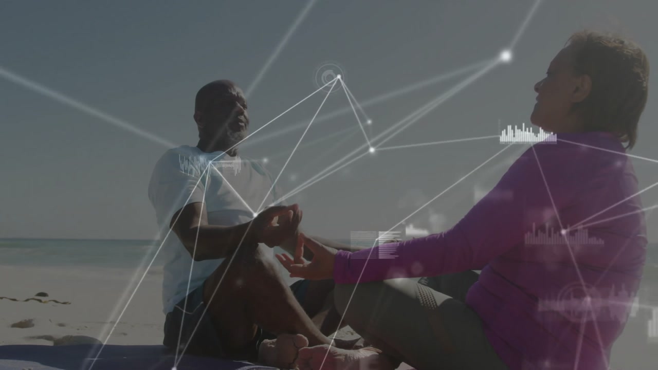 Mature couple meditating on sand holding hands, breathing animating network showing health metrics