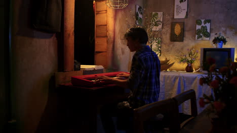 asian man playing piano in dim lit house at night