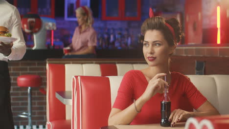 waiter serves a yummy burger to a pin up girl