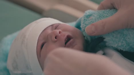 Eine-Vorsichtige-Mutter-Zieht-Einen-Flauschigen-Blauen-Body-Für-Neugeborene-An