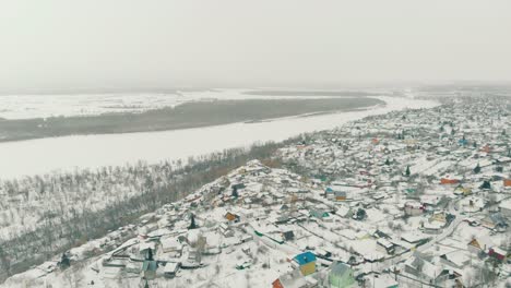 Paisaje-Invernal-Con-Ciudad-Por-Bosque-Y-Vista-Aérea-Del-Río