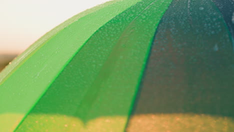 clear water drips down from rainbow parasol raindrops cascade out of turning umbrella edge closeup