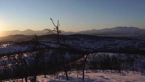 toma panorámica de un paisaje invernal con el sol saliendo y poniéndose sobre una ciudad en la distancia