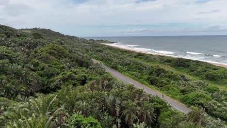 Aerial-shot-of-an-SUV-driving-along-the-beach-at-the-famous-divers-paradise-Aliwal-Shoal-Reef-Beach-near-Scottburgh,-South-Africa