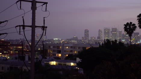beautiful purple california sky during sunset above downtown buildings and palm trees as planes fly over