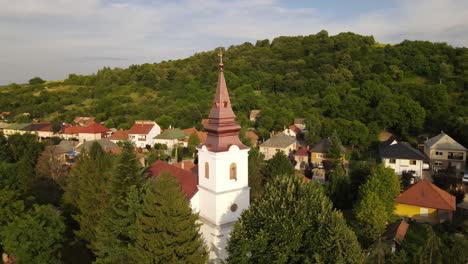 aerial parallax around steeple of small church in village near varbo, hungary