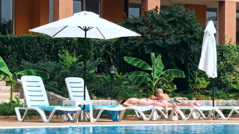 people sitting by the poolside of a resort swimming pool