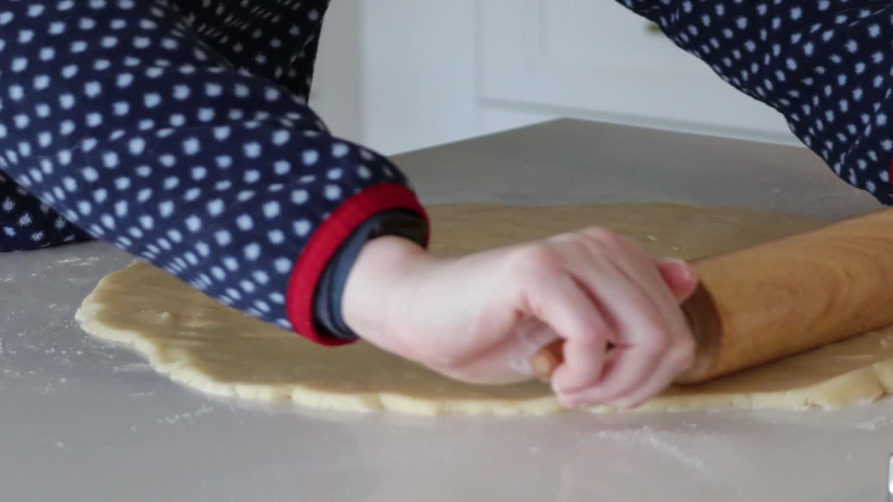 Un primo piano di un mattarello che stende la pasta frolla per la cottura