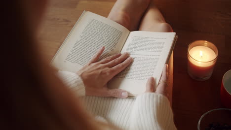 overshoulder,-beautiful-young-blonde-woman-reading-a-book-in-cozy-living-room