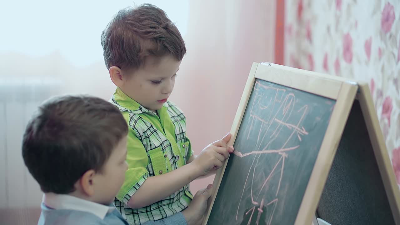dos hermanos pequeños pintan en un caballete