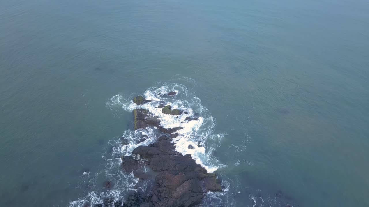 olas marinas chapoteando contra la costa rocosa en la playa de galgibaga, sur de goa, india - de arriba hacia abajo, órbita aérea