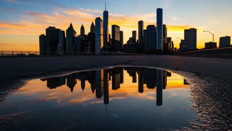 a stunning cityscape reflection during sunset: the silhouetted skyline of skyscrapers mirrored in a puddle against the colorful evening sky