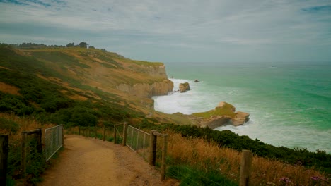 Toma-Manual-De-Los-Acantilados-A-Lo-Largo-De-La-Costa-En-Nueva-Zelanda-Mientras-Camina-Por-Un-Sendero-En-Una-Pendiente