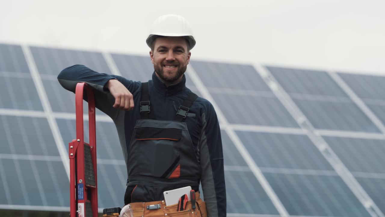 Portrait of a young man in a work uniform with a toolbox in his hands on the background of a solar power plant