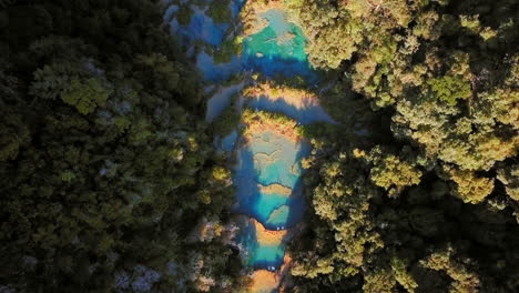 vue aérienne de plusieurs piscines turquoise champey, soirée d'été, top shot pull back