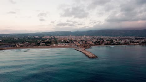 Drone-orbit-over-the-sea-above-Avola,-a-small-historical-town-in-Sicily-Italy