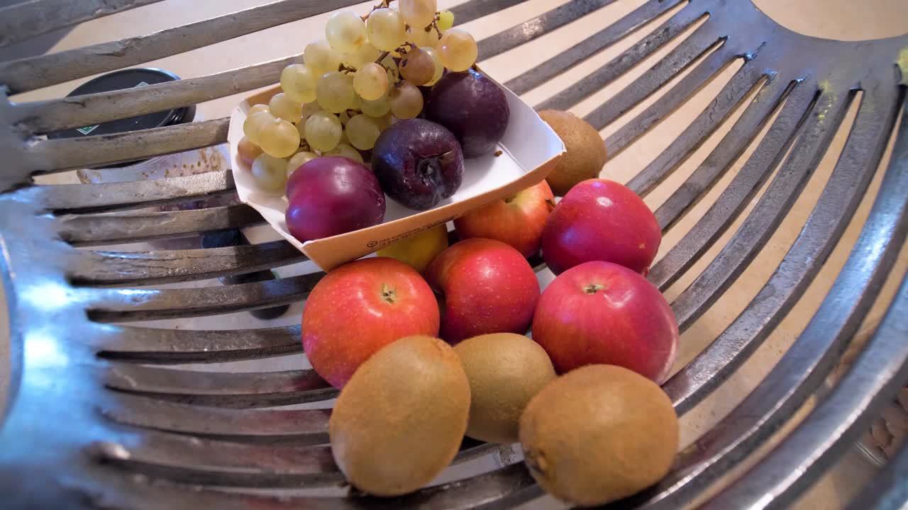 A dining table adorned with fruits in a metal bowl, set within the cozy interior of a household at Maison Goult, France. Rustic charm and modern simplicity, offer a warm and inviting atmosphere.