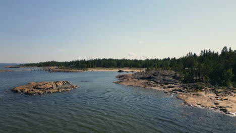 Summer-houses-and-cabins-on-the-rocky-coast-of-Finland,-aerial-shot-in-summer