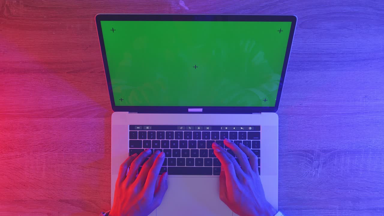 vista de cima para baixo de um computador portátil com maquete de tela verde chromakey exibição em uma mesa de escritório de madeira ao lado do caderno com canetas, copos e um copo de água. zoom lento para fora, fechar