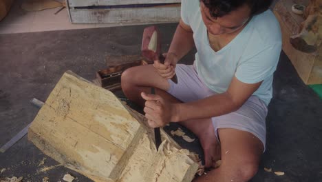 a balinese artist expertly carve a barong mask using a chisel and mallet