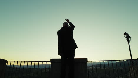 silhouette of a man looking out from the balcony and happily greeting the people