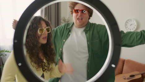 young bloggers dancing in front of ring light, recoding video content at home