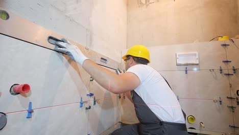 a young builder lays ceramic tiles on the wall