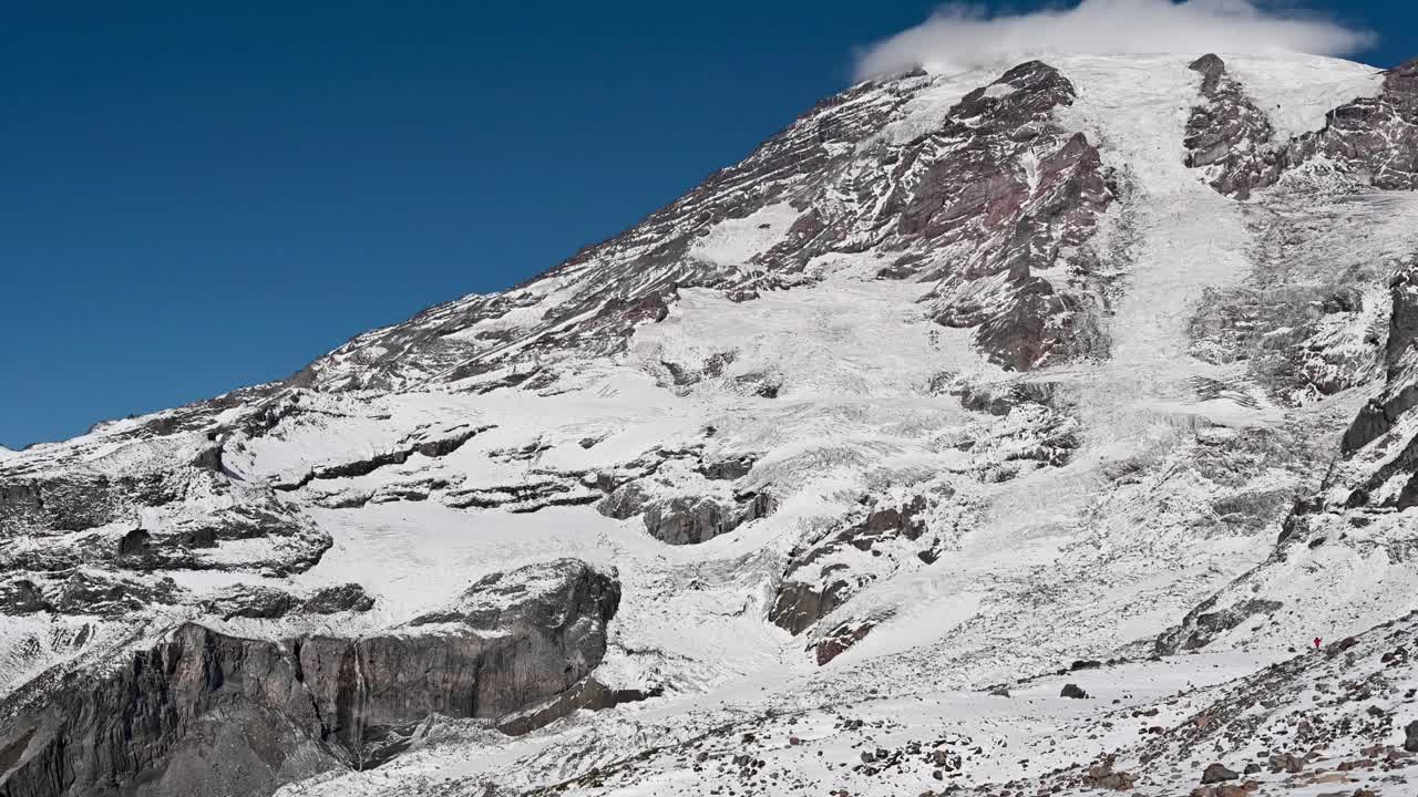 Dramatic aerial view of Mount Rainier’s snow-covered slopes and rugged rock formations in bright winter light