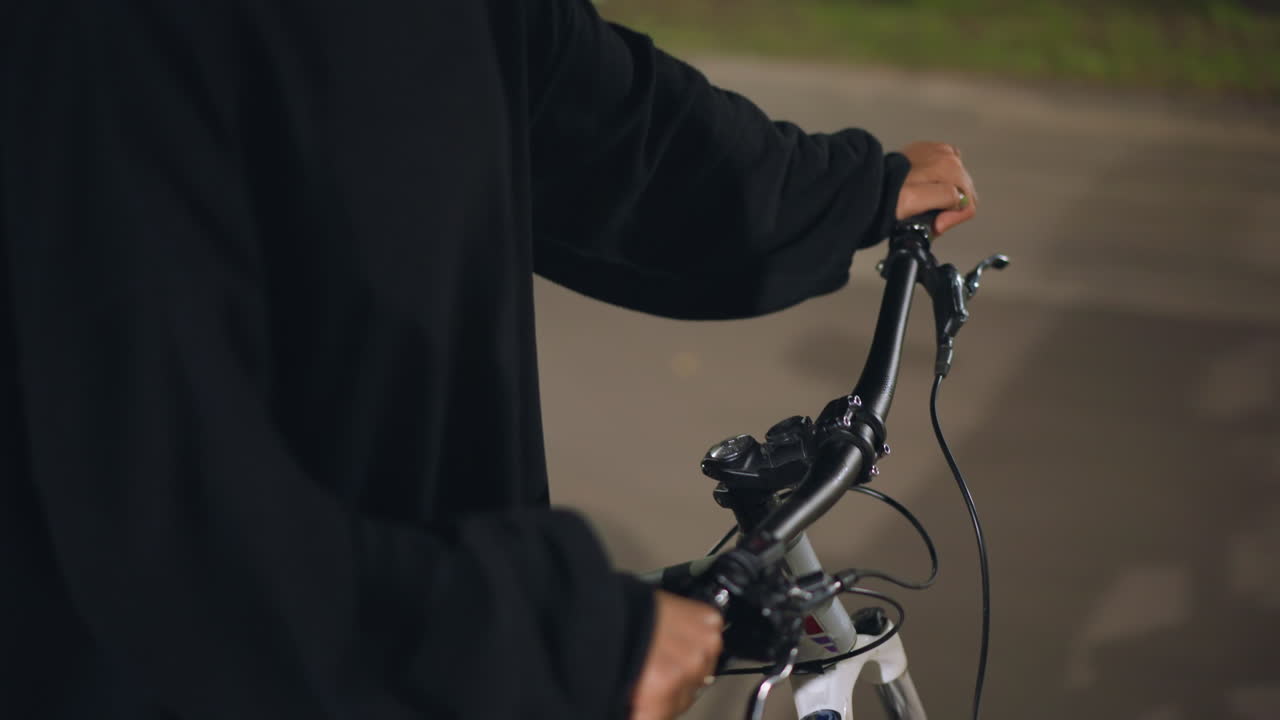 Empty Street Push Of Bicycle At Night, Person In Dark Hoodie Walks Bike Across Intersection With Subtle Motion Blur, CloseUp Of Hands On Handlebars And Steady Frame, Contemplative Nocturnal Journey