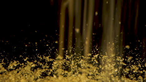 Brown-sugar-crystals-falling-an-bouncing-on-camera-sliding-backward