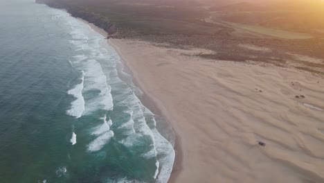 Cinematic-aerial-establishing-at-sunrise-from-Praia-da-Bordeira-in-the-region-of-Algarve,-Portugal